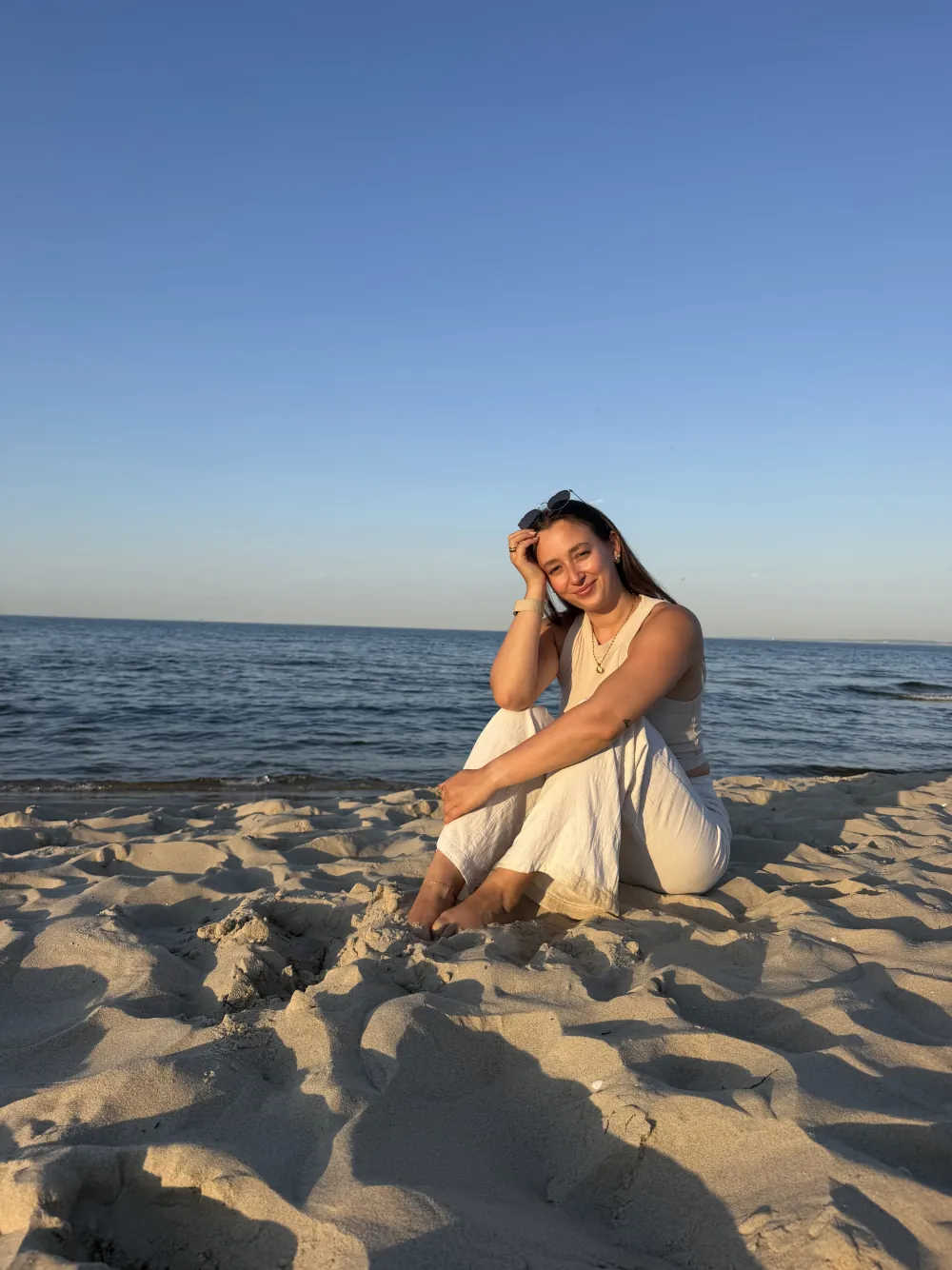 Prisca Cerny sitzt bei Sonnenuntergang lachend am Ostseestrand